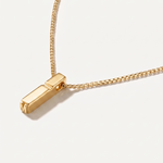 Gold necklace with a rectangular pendant on a light background