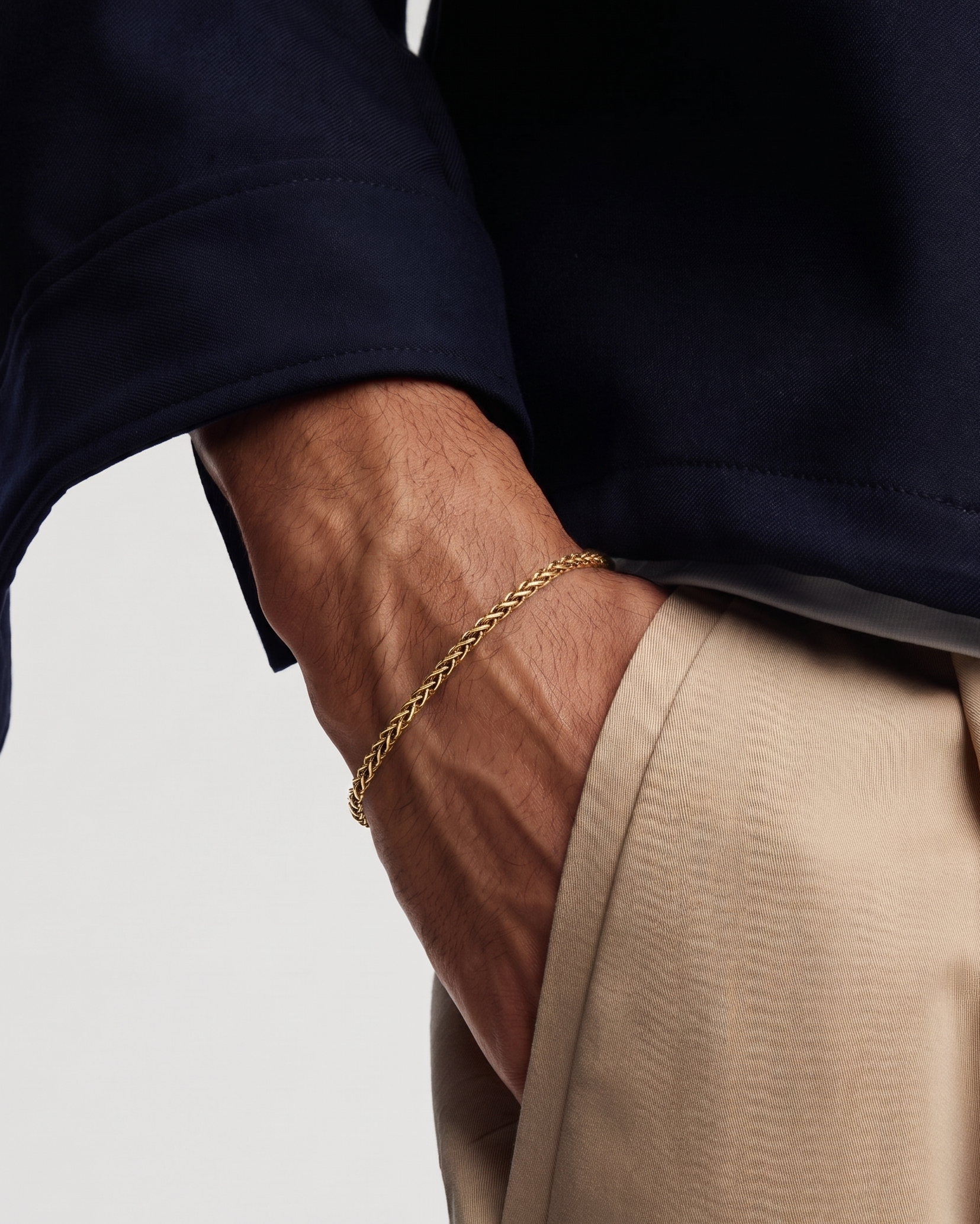 Close-up of a person wearing a gold bracelet on a plain background